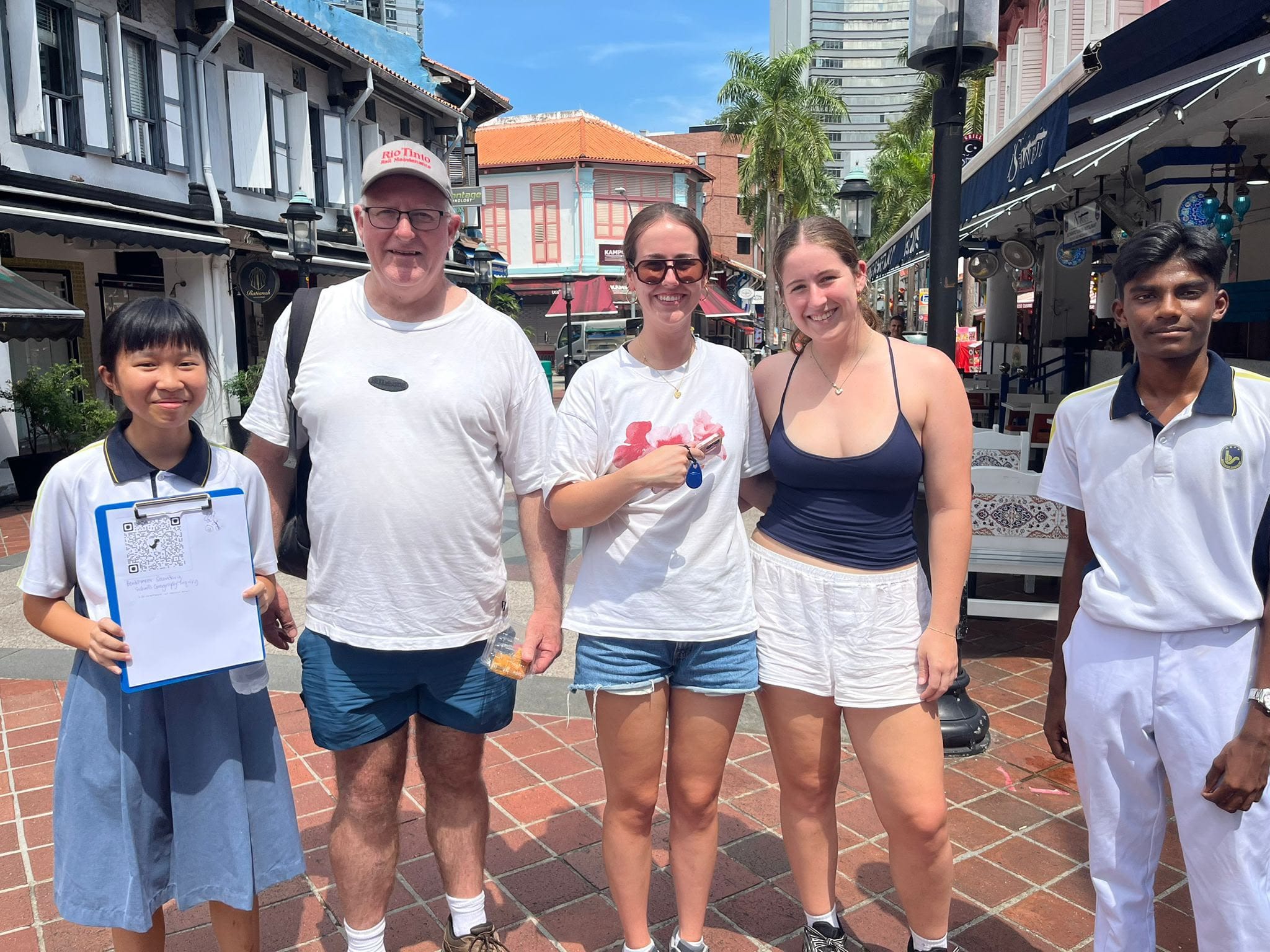 Two students posing with 3 tourists outdoors